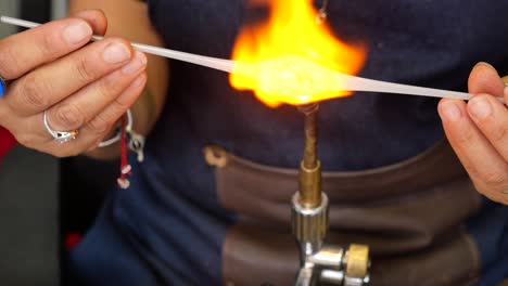 a glassblower uses a torch to heat and melt glass in a workshop