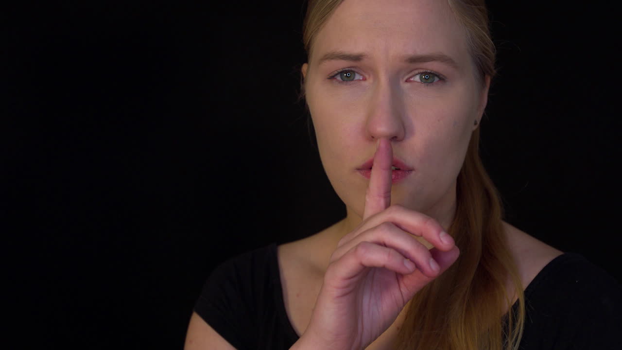 슬픈 겁에 질린 여자가 입술에 손가락을 대고 비밀을 묻다