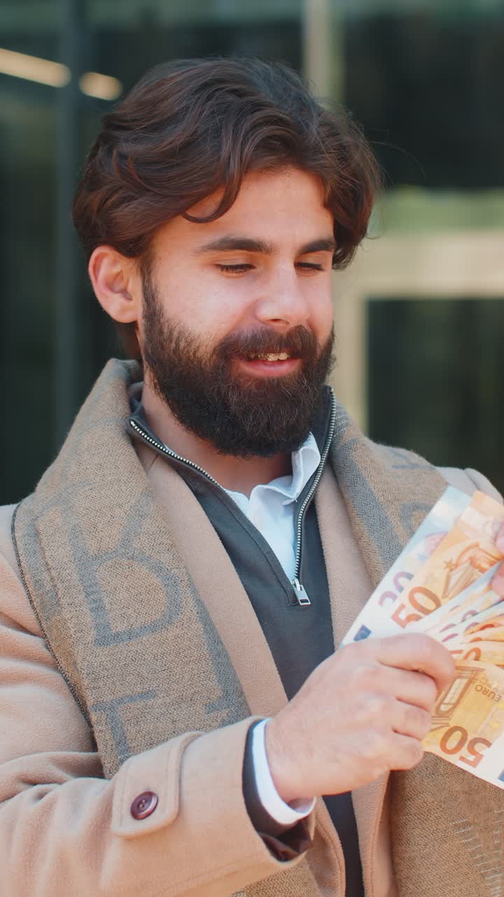 Successful rich happy young indian man holding euro bill money cash fan on downtown city street