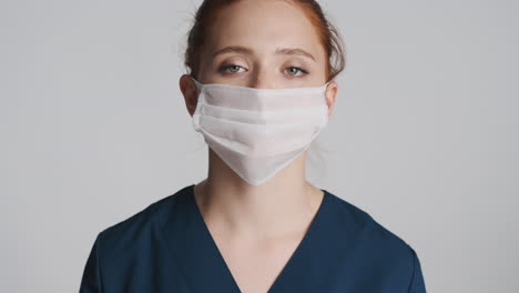 redheaded doctor in front of camera on gray background.