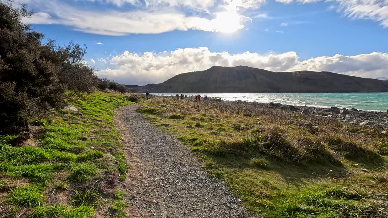Gravel path winds by lake, mountains, and native plants
