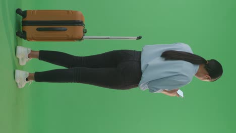 woman with luggage looking at phone on green screen