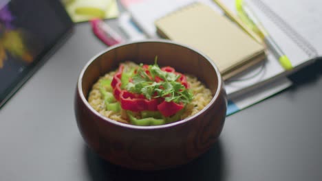 close-up man leaves wooden bowl of colorful tasty ramen noodle on the desk-table at co-working space during lunch time slow-motion