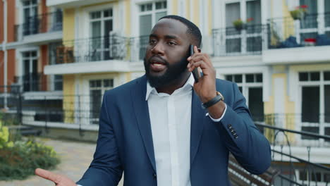 African-businessman-calling-cellphone-at-urban-street.-Afro-man-walking-outdoors