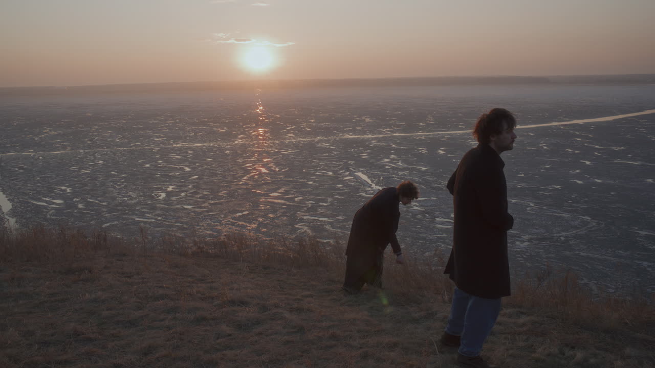 Couple Wandering and Talking on Shore of Frozen Lake at Sunset
