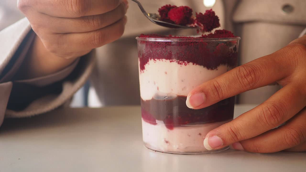 Primer plano de una mano comiendo un postre de terciopelo rojo con una cuchara