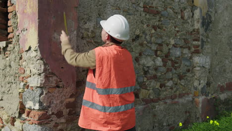 engineer measuring the height of an old wall to rebuild
