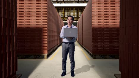 full body of an asian male professional worker with his laptop with red brick packed in stacks are stored, he observes by looking around before he come to concentrating with his laptop