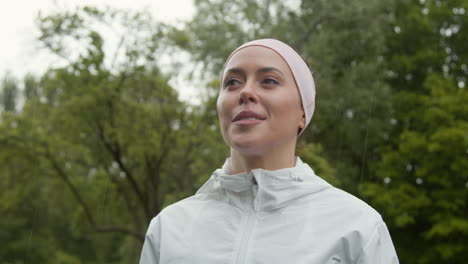 primer plano de una mujer con una cinta para la cabeza haciendo ejercicio manteniéndose en forma corriendo bajo la lluvia 4