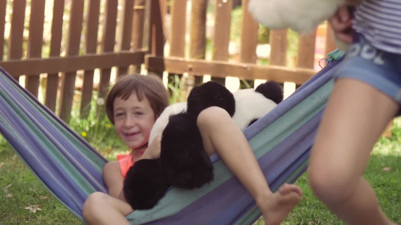 jóvenes niñas felices en el campamento de verano acostadas en hamacas coloridas relajándose jugando afuera con peluches muñecas de perro en el campo de hierba verde niños niños en cámara lenta