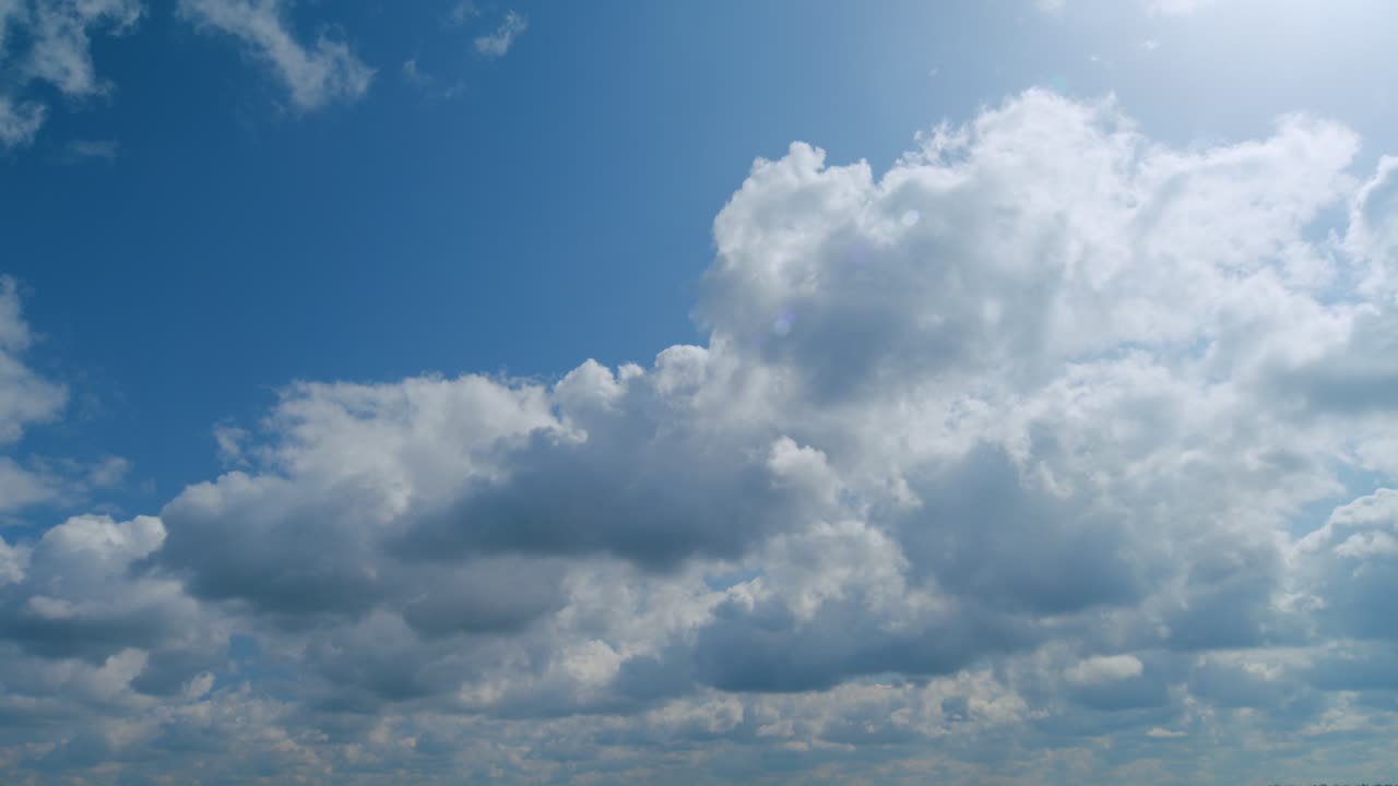 Summer blue sky with fluffy white clouds. White clouds float across the blue sky. Time lapse.
