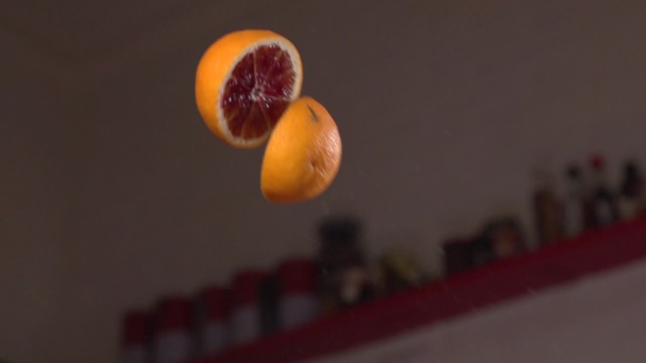 toma en cámara lenta de un cuchillo afilado cortando una naranja en el aire estilo ninja de frutas