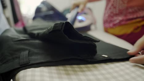 Closeup-of-a-woman-ironing-clothing-by-stream-iron-on-board-at-home