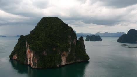 drone footage of islands in thailand with limestone rock formation sticking out of the water and the ocean in background-15