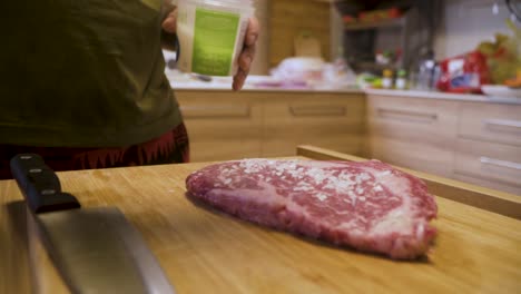 cook sprinkling salt on a4 wagyu steak on a wooden chopping board