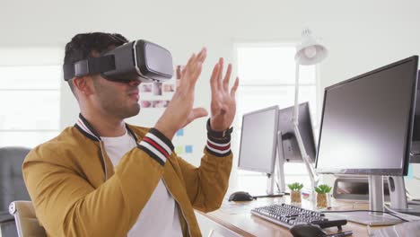 Mixed-race-man-wearing-VR-headset-in-creative-office