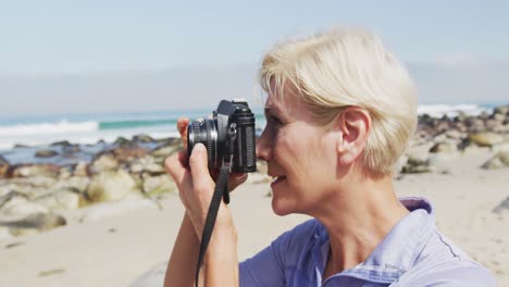 Ältere-Wanderfrau,-Die-Mit-Einer-Digitalkamera-Am-Strand-Fotografiert.