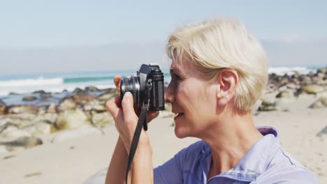 senior hiker woman taking pictures using digital camera on the beach.