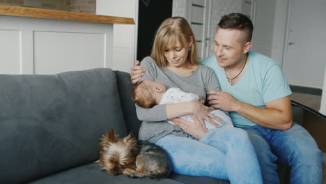 Happy-Family-Spends-Time-Together-Mother-Father-And-Son-Two-Months-Sitting-On-A-Couch-Playing-With-T