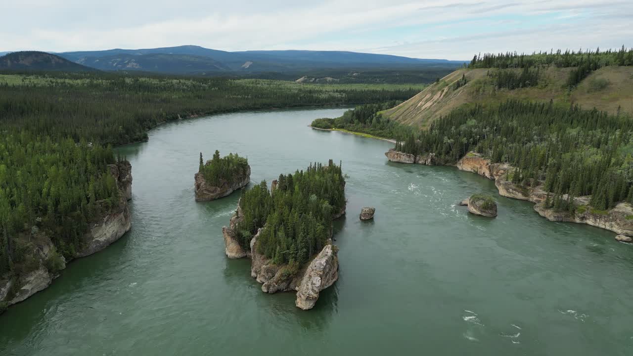 Langsomt luftig overblikk over Five Finger Rapids i Yukon, Canada, som viser grønne stryk, detaljerte steiner, omkringliggende skog, fjell og overskyet himmel