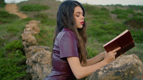 Dreamy-romantic-girl-reading-sitting-at-nature-leaning-on-rocky-hill-close-up.