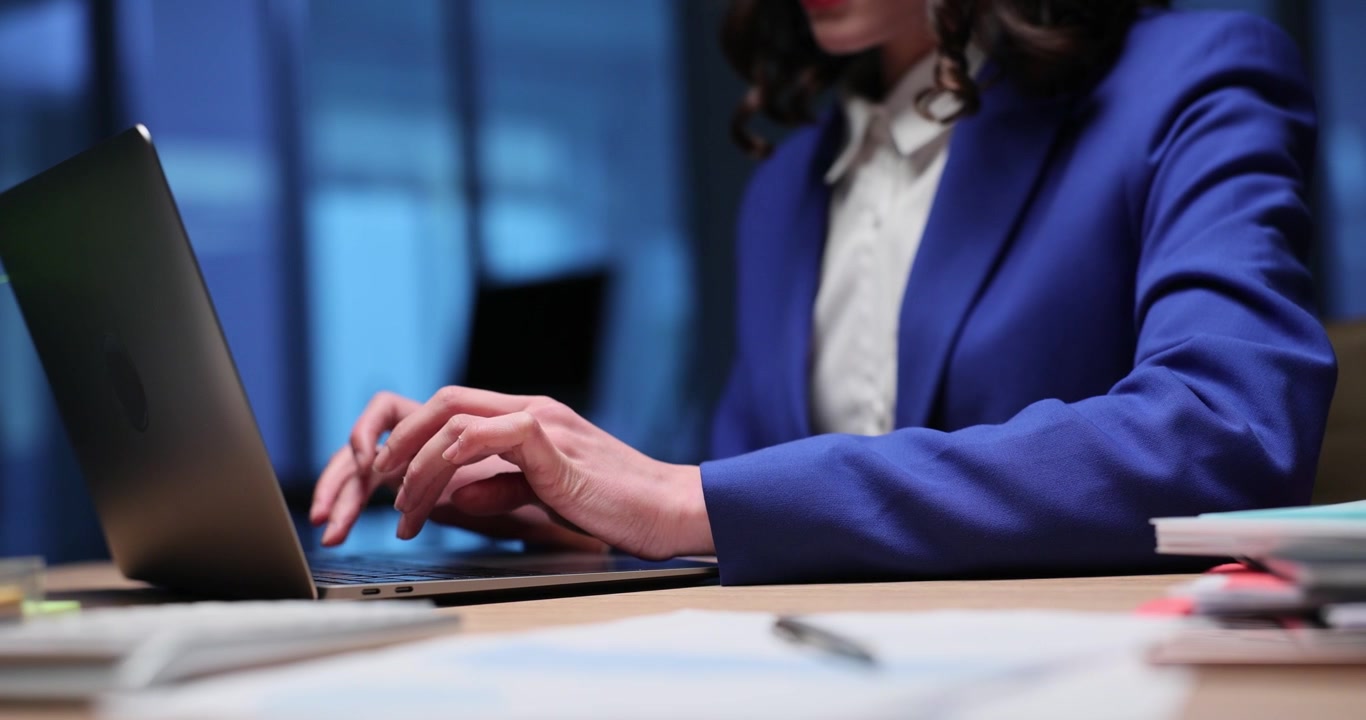 Forretningskvinne jobber sent på kvelden, fokuserer på laptop ved skrivebordet