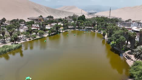 oasis del desierto huacachina, perú con lago y palmeras, con grandes dunas de arena en el fondo