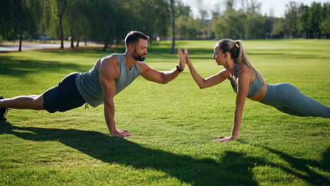 couple high-fiving while doing planks in a park