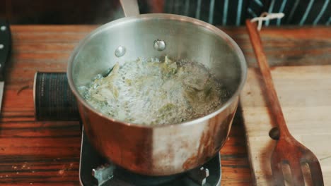 boiling spinach leaves on a propane camping stove
