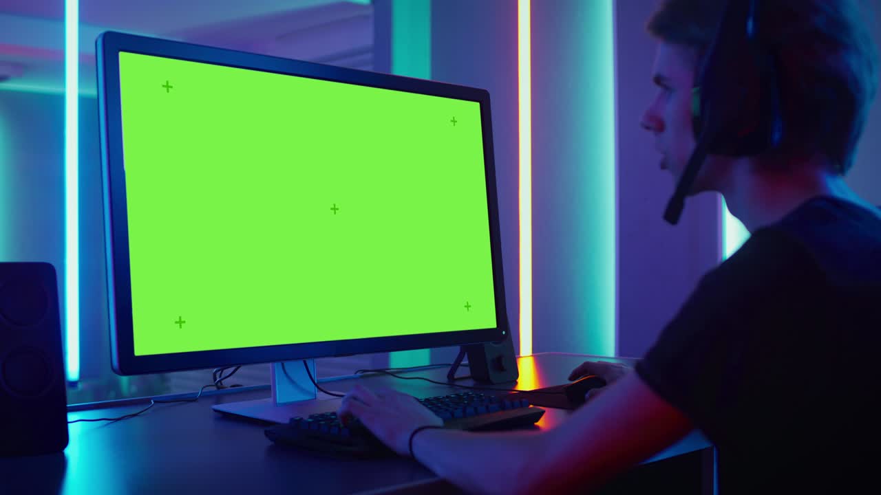 pro gamer che gioca a videogiochi sullo schermo verde del suo computer personale. parla con la sua squadra attraverso il microfono sulle cuffie. sala al neon retro.