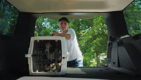 una mujer carga la jaula con cachorros en la cajuela de un auto y consigue un perro de un concepto de refugio