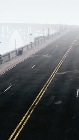 camino vacío que conduce al puente en la niebla