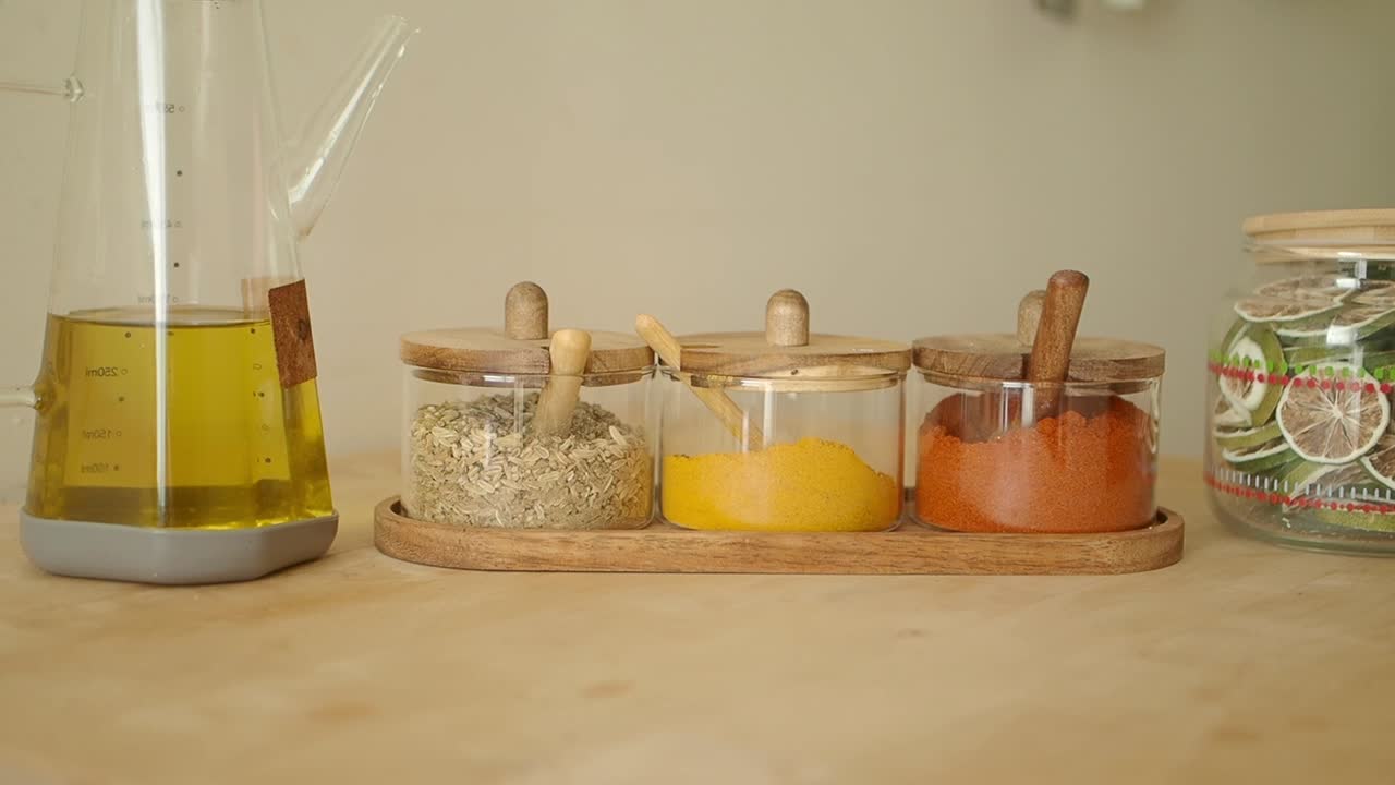 Olivenoliekande glider hen til krydderier og tørrede limefrugter på køkkenbordet.
