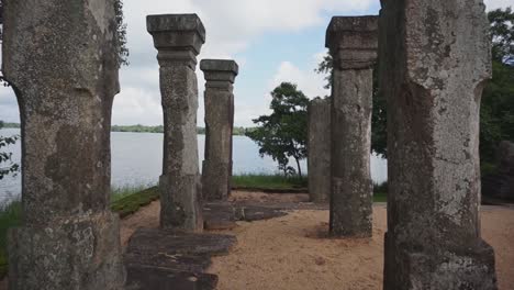 Tall-stone-pillars-in-a-temple-ground,-near-a-lake