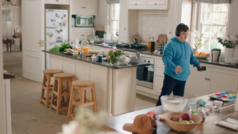 happy teenage boy with down syndrome dancing in kitchen having fun celebrating listening to music wearing headphones enjoying weekend