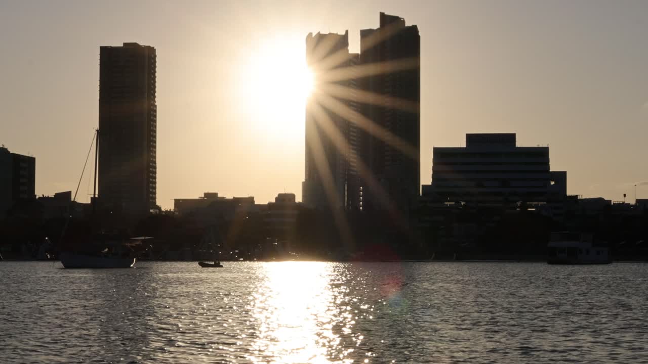 Pôr do sol atrás de edifícios com reflexos na água
