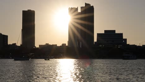 puesta de sol detrás de los edificios con reflejos en el agua