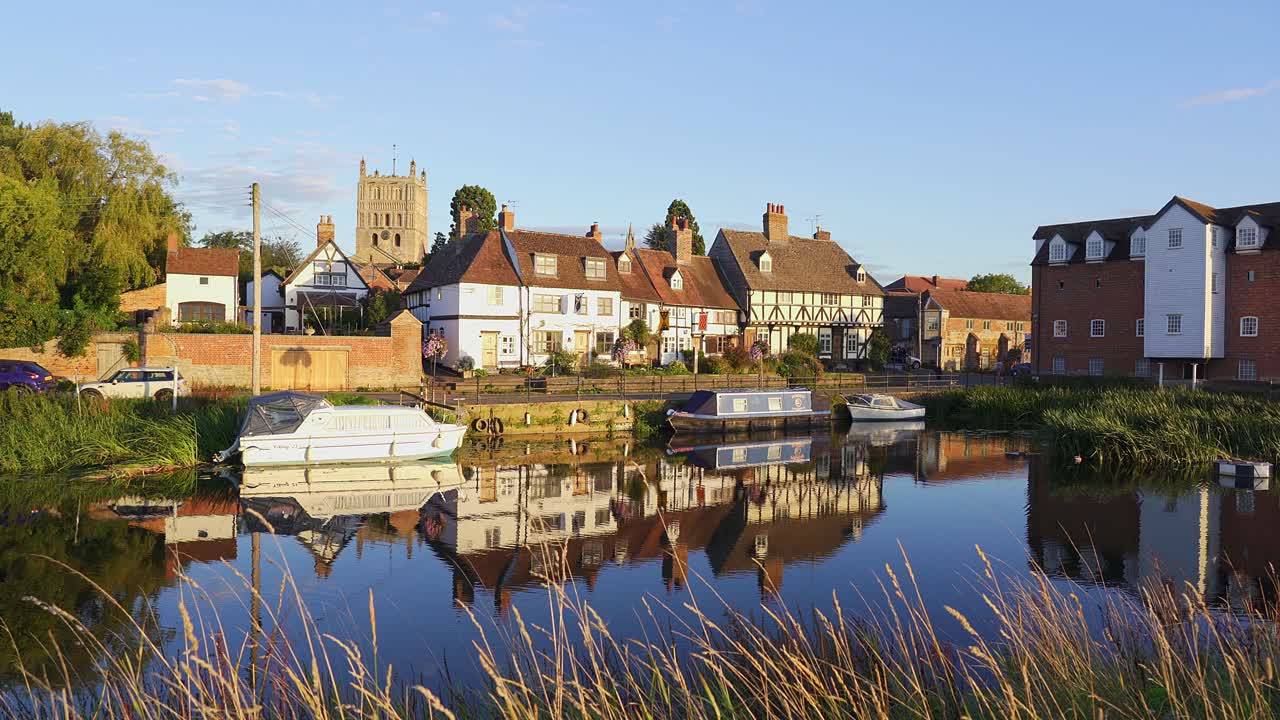 Tewkesbury, históricas casas con entramado de madera reflejadas en el río con la torre medieval de la iglesia abacial al fondo