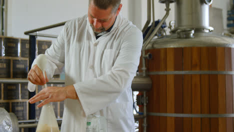 male worker stirring liquor in flask 4k