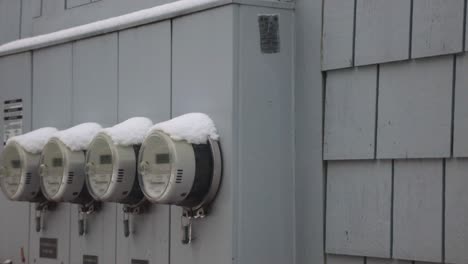 four hydrometers locked and capped with snow on the gray wall