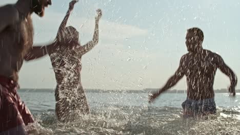 friends splashing in lake on summer day