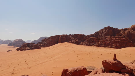 Pan-across-Wadi-Rum-cliff-vista-overlooking-desert-dunes