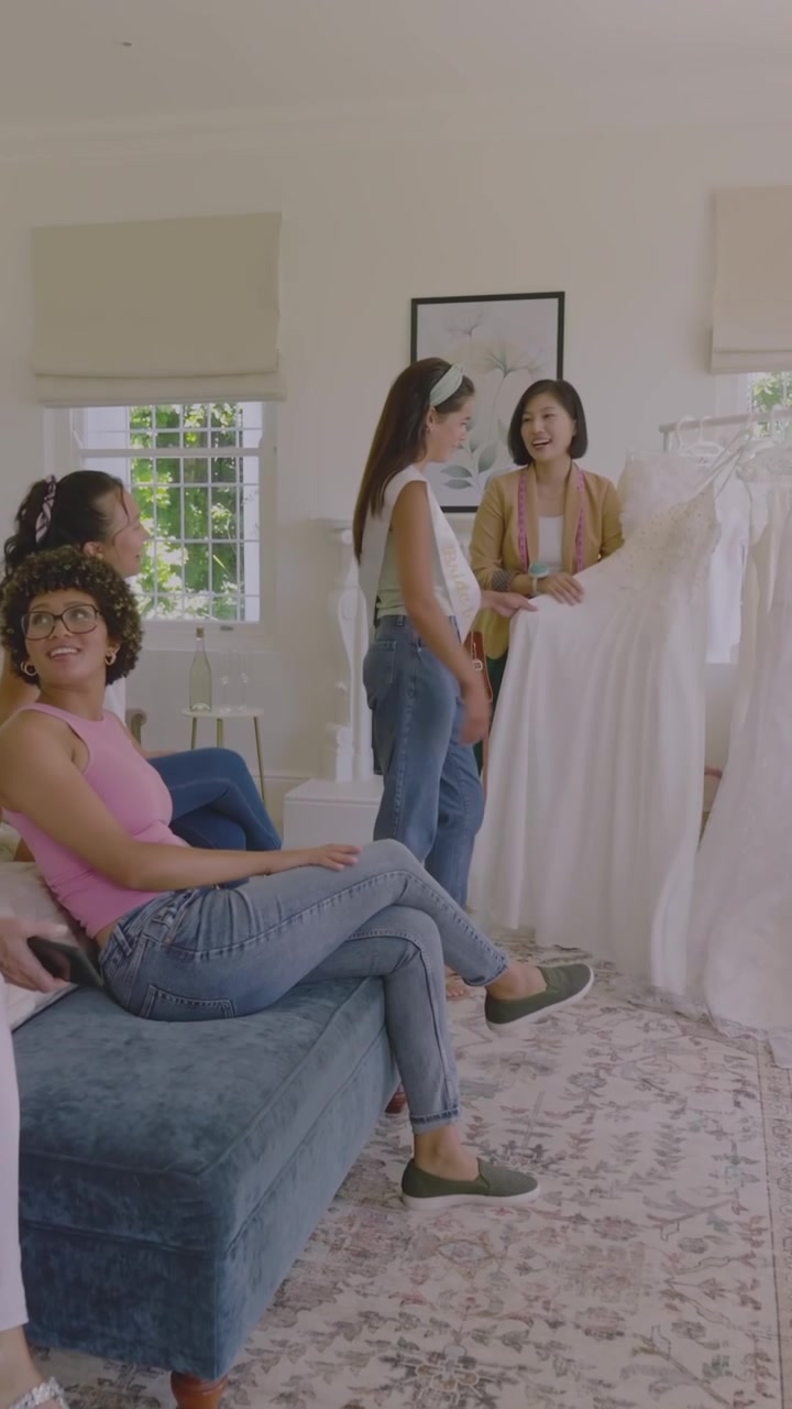 Vertical video: Diverse women arriving, greeting at home, sash bride inspecting gowns for wedding