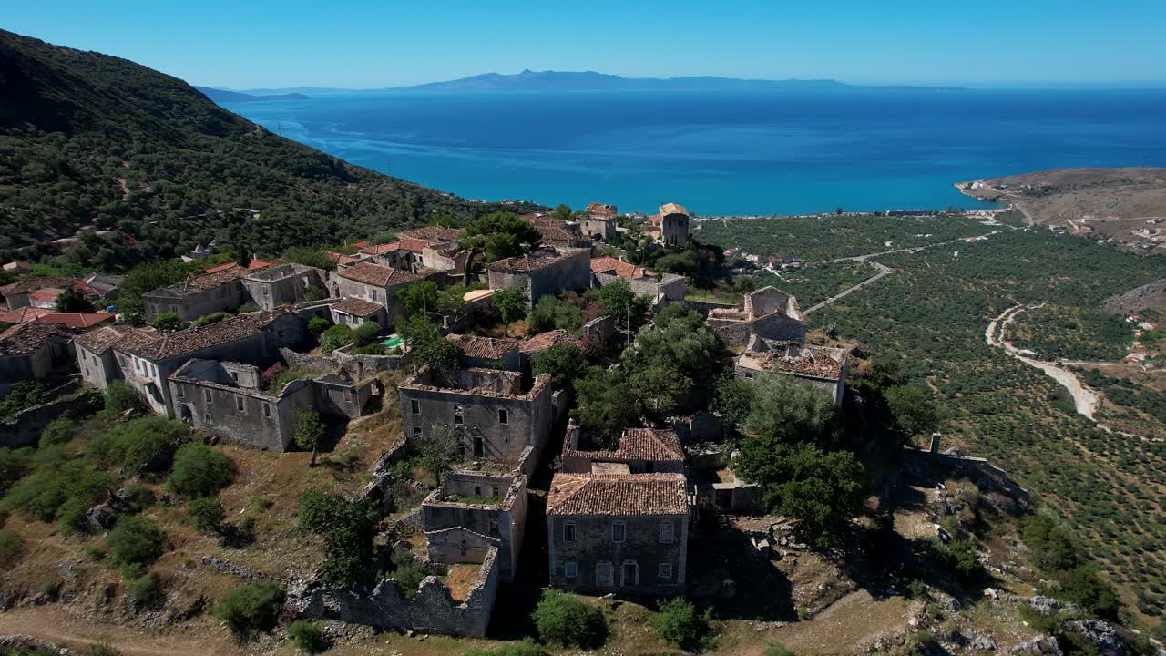 pueblo mediterráneo con casas de piedra construidas en un acantilado rocoso con vistas a la impresionante costa del mar jónico en albania
