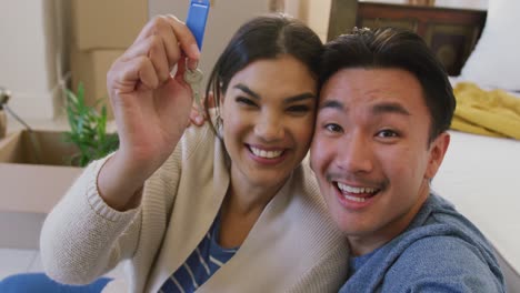 Video-of-happy-diverse-couple-holding-keys-to-new-house