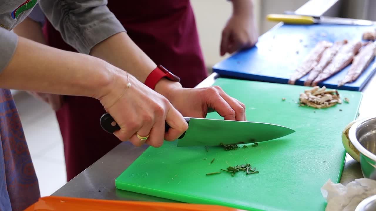 шеф-повар режет зелень на кухне ресторана.