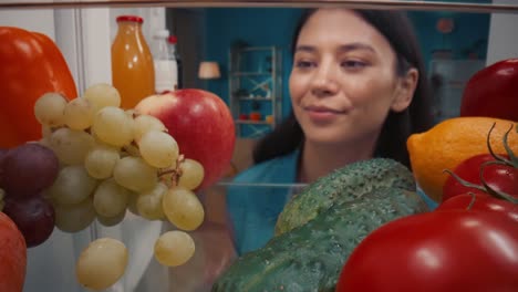 woman looking inside a refrigerator full of fresh produce