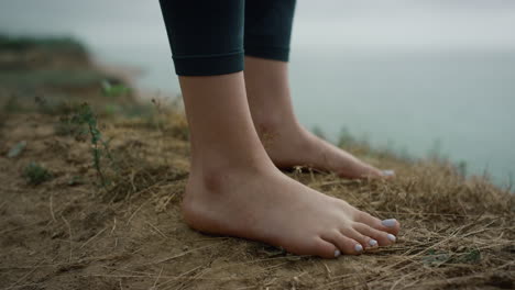 girl legs standing hilltop closeup. unknown barefoot woman relaxing on sea beach