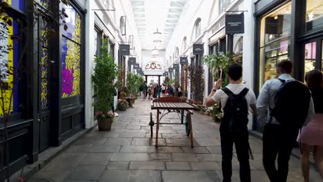 designer boutique shops in covent garden, showing tourists browsing and walking through the undercover market street, london, uk