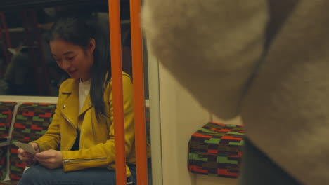 mujer sonriente sentada en un carruaje en el tren subterráneo mirando fotos 1